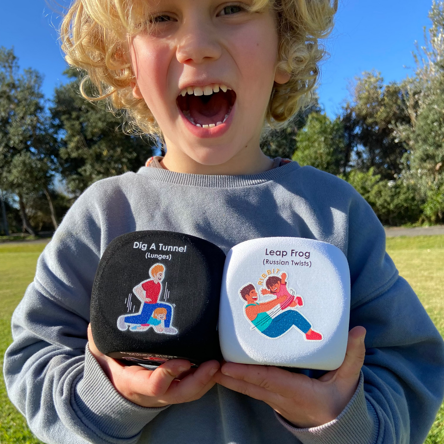 Child holding two educational toys outdoors on a sunny day